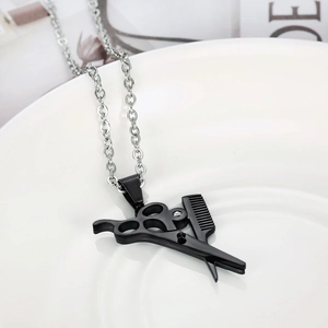 Detailed view of black scissors and comb pendant on a silver stainless steel chain