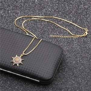 Golden sunburst pendant necklace with colorful micro-inlaid zircons on black background