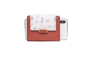 Close-up of brown PU leather wallet with leaf print flap and gold clasp next to a phone