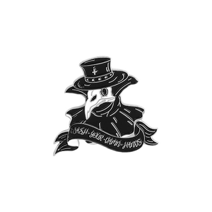 Detail of plague doctor enamel pin featuring black bird mask and wash your hands slogan