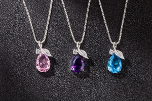 Detail view of pink, purple, and blue teardrop crystal necklaces with leaf zirconia accents
