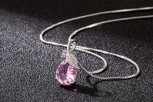 Macro shot of pink waterdrop pendant with leaf-shaped diamond accents on a silver chain