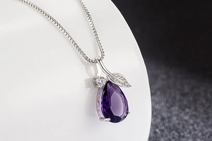 Detail of purple teardrop gemstone pendant with sparkling leaf design on silver chain