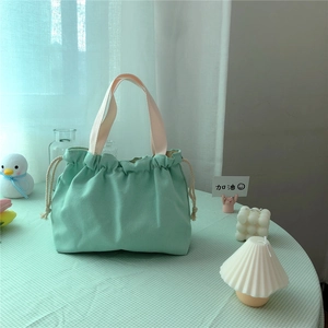 Detail of mint green canvas drawstring tote bag with off-white webbing handles