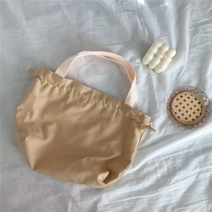 Detail of khaki canvas tote bag with pink handles and practical drawstring closure