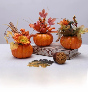 Detailed view of three decorative foam pumpkins with autumn sunflowers and maple leaves