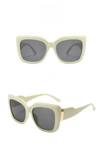 Dettaglio degli occhiali da sole squadrati beige con cerniere in metallo dorato