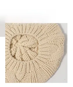 Top macro view of beige cable knit beret showing textured radial twist pattern detail