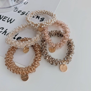 Detail of high-elasticity hair ties with pearls and crystals and handmade metal tags