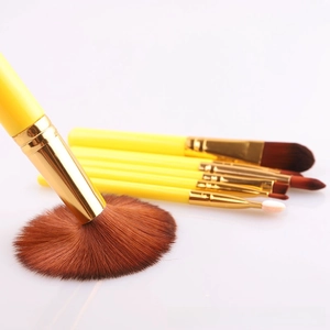Macro detail of high-quality yellow makeup brush set with soft synthetic bristles and gold ferrule