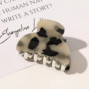 Detail view of cream and black tortoiseshell acrylic hair claw clip with silver metal teeth