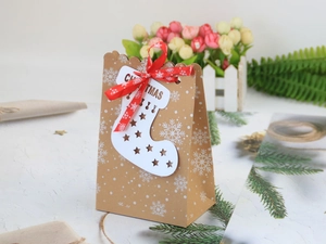 Weihnachtliche Kraftpapiertüte mit weißen Schneeflocken, rotem Band und Socken-Anhänger