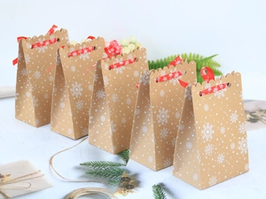 Brown kraft paper Christmas gift bags with white snowflake patterns and red ribbons