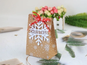 Weihnachtstüte aus Kraftpapier mit rotem Band, Schneeflocken-Anhänger und festlicher Karte