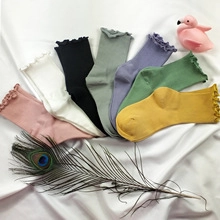 Flat lay of colorful cotton socks with ruffle cuffs on white silk background