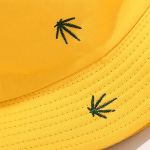 Close-up of green leaf embroidery and yellow twill cotton fabric on a bucket hat