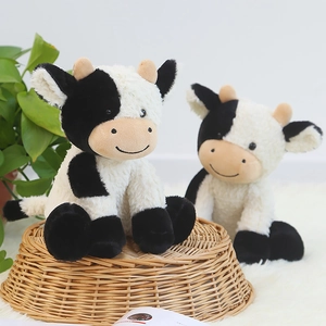 Lindo muñeco de vaca de peluche en blanco y negro sentado para regalo infantil