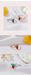 Detail of strawberry rings with red heart stones and green leaves in silver and rose gold