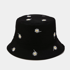 Detailed view of white daisy floral embroidery on black cotton bucket hat fabric