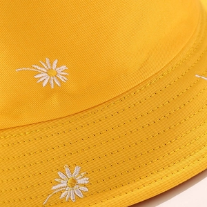 Close-up of yellow cotton bucket hat with white daisy embroidery and fine stitching