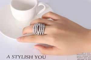 Detail of silver multi-layer crisscross ring with pavé diamonds on a hand holding a cup