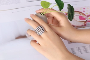 Close-up of sparkling multi-layer pavé silver ring worn by a model on artistic background