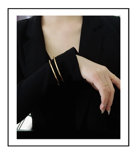 Minimalist gold-plated stainless steel bangles and rings shown on a black suit sleeve