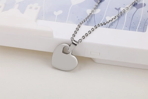Close-up of a silver heart pendant on a cross chain with smooth metallic finish