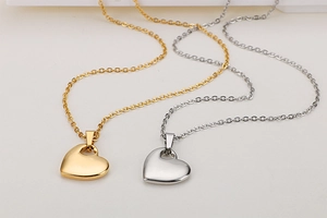 Close-up of heart-shaped pendants in gold and silver finish with elegant metal chains