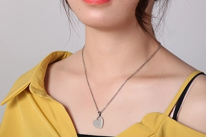 Close-up of a minimalist silver heart pendant necklace worn on a woman neck