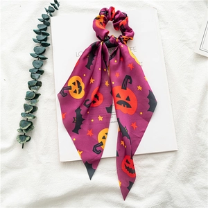 Close-up of a satin Halloween hair scrunchie with orange pumpkin and black bat patterns