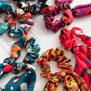 Flat lay detail of satin hair scrunchies with Halloween pumpkin and bat printed patterns