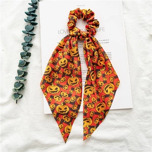 Detail of Halloween hair scrunchie with pumpkin print on red and black plaid satin fabric