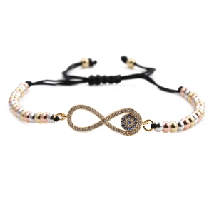 Macro detail of tricolor metal beads and infinity evil eye charm on black woven bracelet