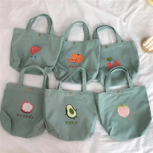 Detailansicht von sechs bohnengrünen Mini-Canvas-Taschen mit süßen Fruchtmotiven und Druckknopf