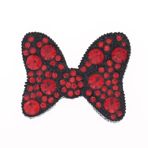 Detail of a black painted bow tie with a central red crystal for DIY phone case decor