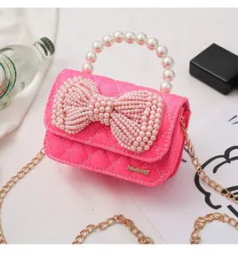 Close-up of pink quilted mini bag with pearl bow detail and golden chain strap
