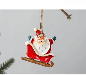 Close-up of Santa on a red sleigh resin ornament hanging from a festive pine branch