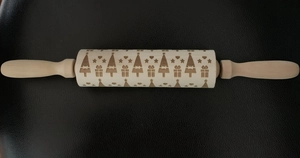 Detailed view of Christmas themed engravings including trees and stars on wooden rolling pin