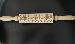 Macro view of Christmas deer and tree engravings on a wooden rolling pin surface