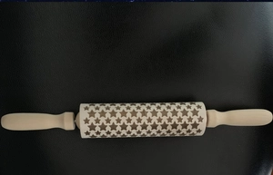 Close-up of wooden rolling pin with engraved five-pointed star patterns and smooth handles