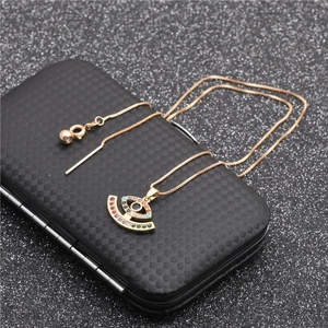 Gold Evil Eye necklace with colored zircons and snake chain on a textured black background