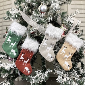 Close-up of four small burlap Christmas stockings with reindeer patterns and white fur cuffs
