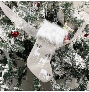 Close-up of beige linen Christmas stocking with white reindeer and faux fur trim
