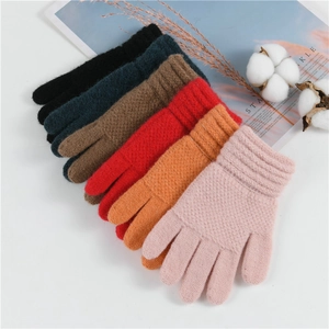 Close-up of six colorful knitted winter gloves for children on a cozy styled background
