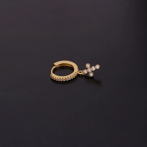 Macro shot of gold hoop earring featuring a cross pendant encrusted with sparkling zircons