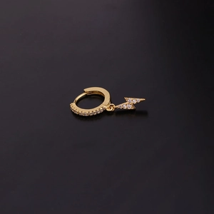 Detailed macro view of a gold-plated lightning bolt earring with sparkling zircons