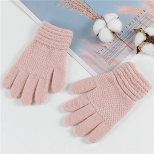 Flat lay of soft pink knitted children's winter gloves with cozy decorative cotton props