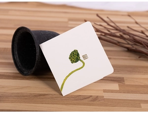Elegant white lotus greeting card with traditional red seal on natural wooden surface