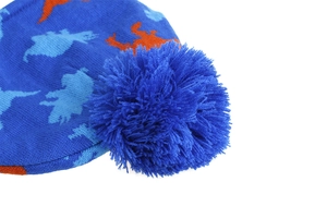 Detailed close-up of knitted winter hat with orange dinosaur pattern and fluffy blue pompom
